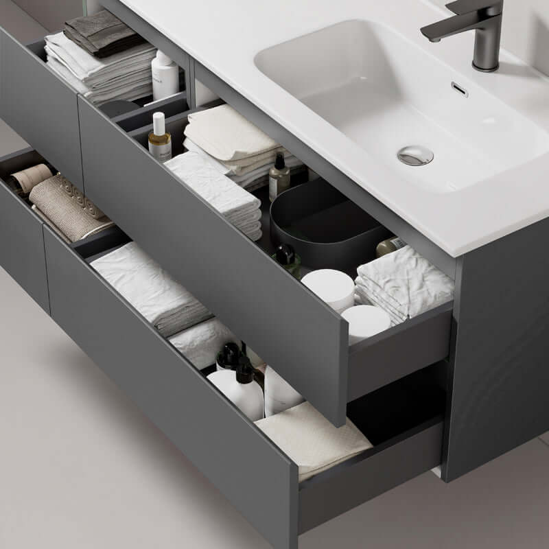 Dettaglio di un mobile bagno sospeso grigio con lavabo a destra, mostrando cassetti aperti con asciugamani e prodotti per la cura. (25686708)