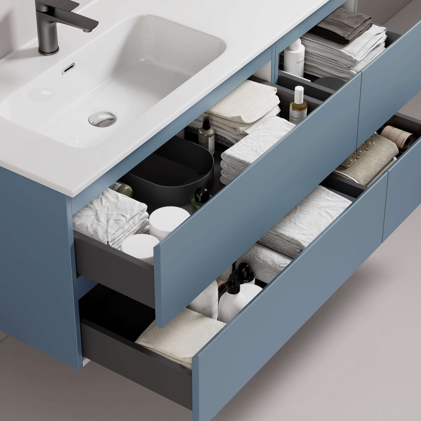 Mobile bagno sospeso blu avio con lavabo, cassetti aperti con asciugamani e prodotti per la cura personale.