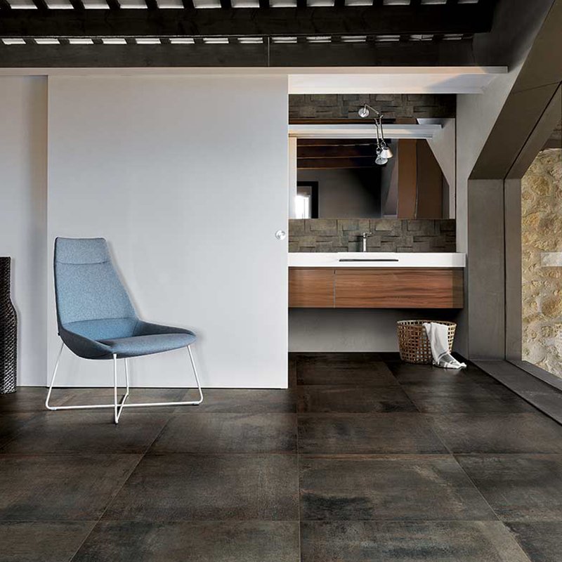 Modern interior featuring Gres Porcellanato Effetto Cemento 80x80 Barrique flooring with stylish blue chair and sleek design.