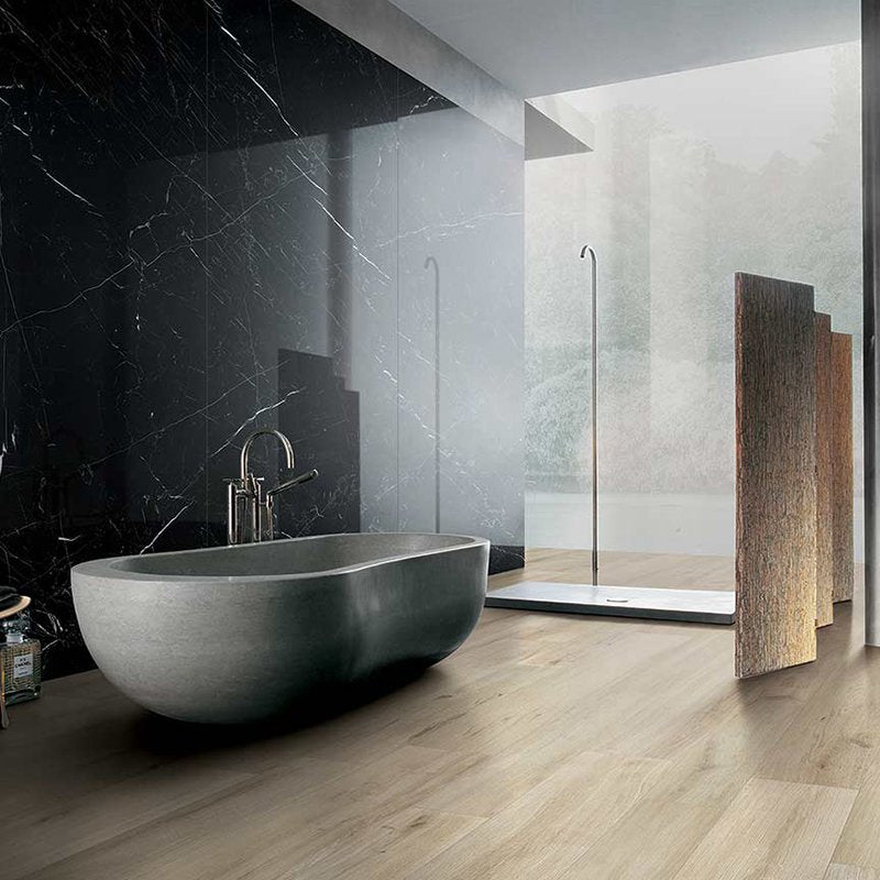 Modern bathroom with a freestanding tub, sleek black marble wall, and natural wood effect tiles from Florim.