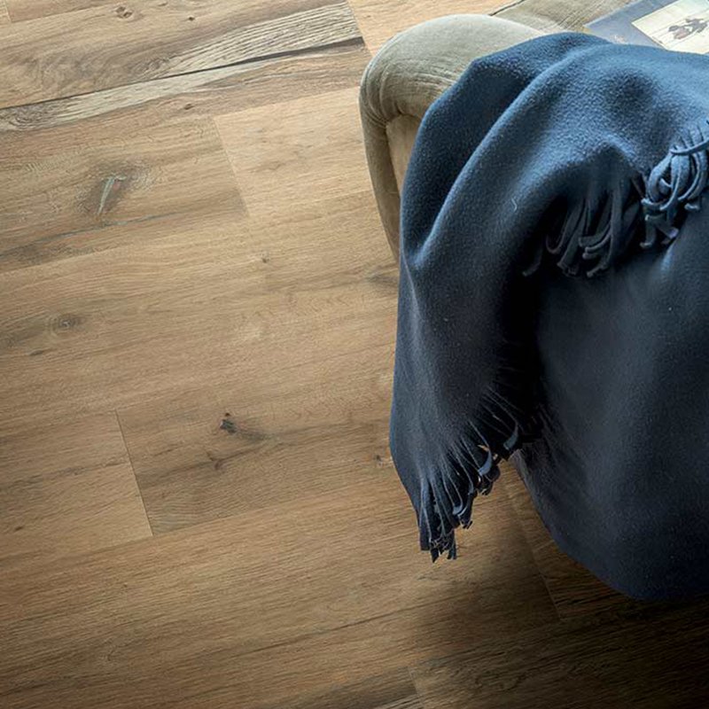 Gres porcellanato effetto legno rettificato naturale 20x120 Noisette su pavimento con coperta blu.