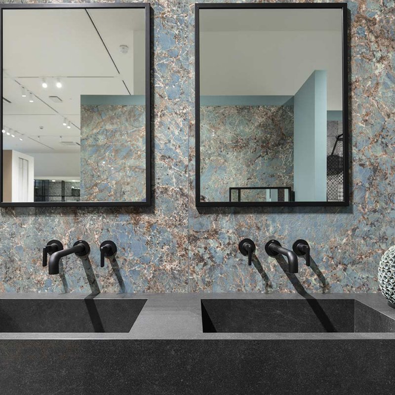 Modern bathroom design featuring a sleek black sink, stylish faucets, and elegant blue marble wall with mirrors.