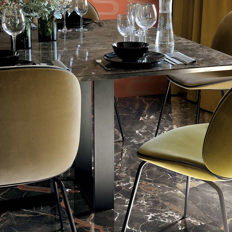 Elegant dining table setup featuring glossy marble effect porcelain tiles by Florim, surrounded by stylish chairs.