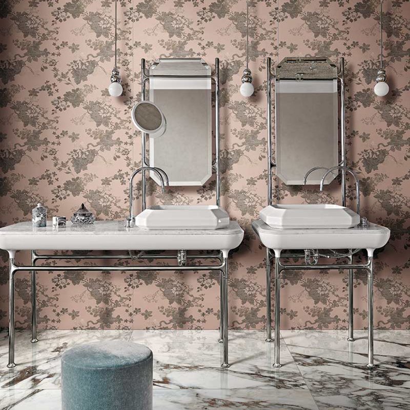 Elegant bathroom with vintage double sinks, mirrors, and floral wallpaper in soft pink tones.