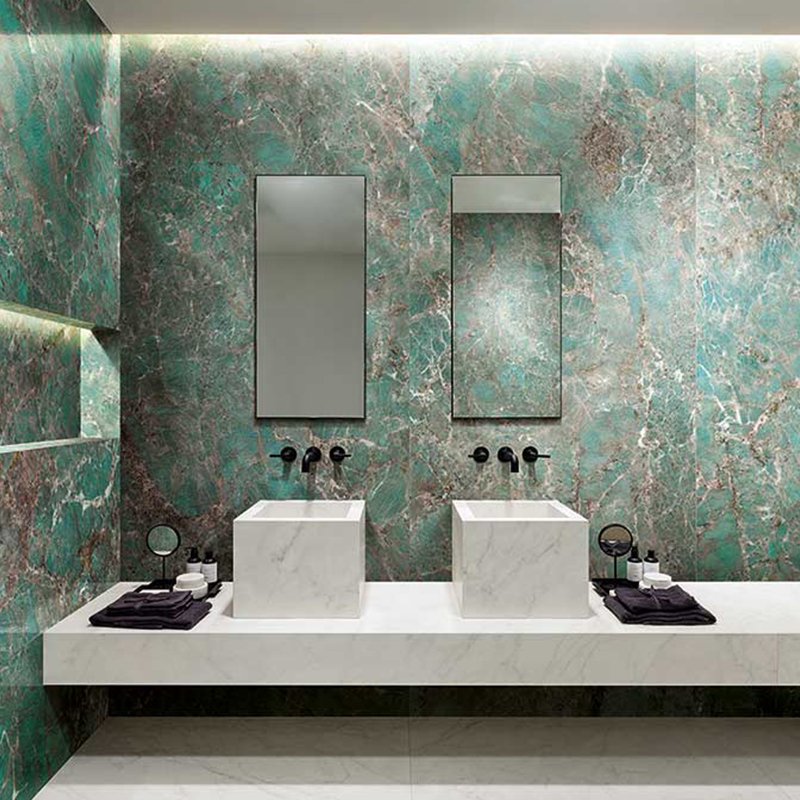 Luxurious bathroom design featuring green marble effect tiles with double sinks and modern mirrors.