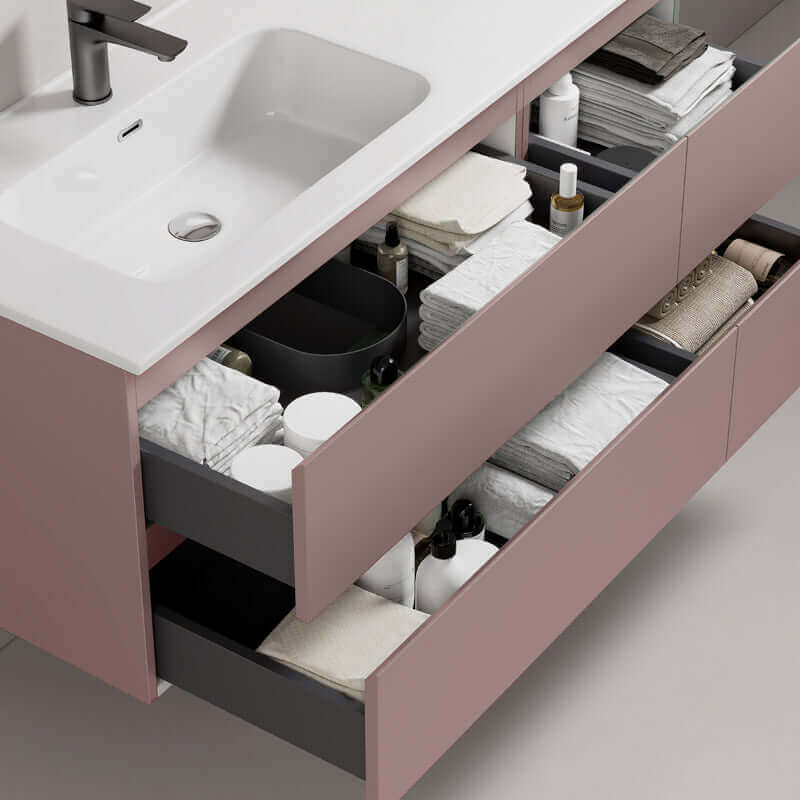 Mobile bagno sospeso rosa retro con lavabo a sinistra e cassetti ben organizzati con asciugamani e prodotti per la cura. (25686846)