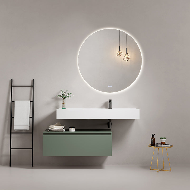 Modern white resin sink with green cabinet and illuminated round mirror in stylish bathroom setting.