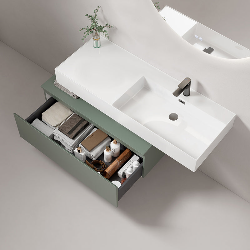 Lavabo sospeso in resina bianco lucido con cassetto verde e accessori bagno organizzati.