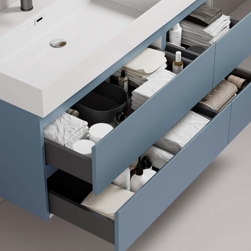 Mobile bagno sospeso blu avio con lavabo e cassetti organizzati, composto da asciugamani e prodotti per il bagno.