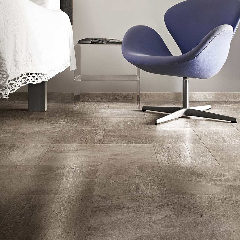 Gres Porcellanato Effetto Pietra Rettificato Grip Ecru Ardoise flooring in a modern bedroom with a stylish chair.